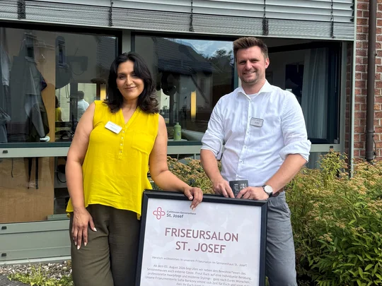 Frau und Mann stehen hinter einem Plakat zur Eröffnung eines Friseursalons