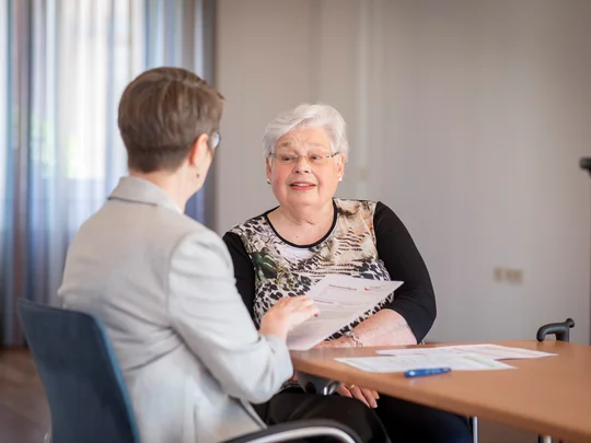 zwei Frauen sitzen an einem Tisch und sprechen miteinander